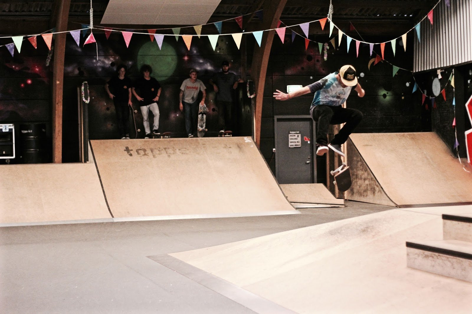 The skatepark at the yellow hall is the indoor skatepark of youth cultural centre, Tapperiet. It consists of all the obstacles one could wish for. The hall is decorated and designed with a good flow in mind. The central element of the hall’s street course is a podium consisting of:Quarterpipe-wallrides, pyramide-hip, bank-to-ledges in two heights, 5 steps and a hubba-ledge made of granite. In addition, there are banks, quarter pipes and bank-to-wall as well as flat curbs and rails. Besides the street course, the skatepark at the yellow hall has a mini ramp which is 1 metre high with a soft transition. The mini ramp is suited for both beginners and more experienced skaters who wish to learn new tricks.The hall also has a common room with couches, a kitchen and a bathroom available.Skating at the hall is free!The opening hours of the hall varies. You can see them for one month at a time on the hall’s facebook page:https://www.facebook.com/skategulehalkoege