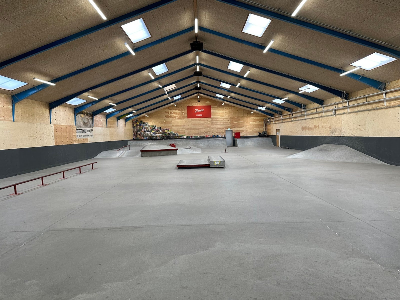 Sønderborg Skatepark is probably the largest indoor park in Southern Jutland. The park has everything a skater could possibly need and very favourable offers for the members of the park.The park has banks and quarter pipes in each end of the park with obstacles in between. The obstacles meet all needs and includes a pyramid box, a flat bar with kink as well as a fly-out.Surrounding the obstacles is everything from practice rails to grind boxes and manual padsEverything in the park is made of wood and steel and seems to be of a good quality.Sønderborg Skatepark is a little unique as it offers its members a great responsibility. For visitors, the park is only open two days a week (Tuesday and Thursday) for a couple of hours, while the members can enjoy opening hours between 2pm and 10pm on weekdays and between 10am and 10pm on the weekends. Members have a chip so that they can always access the park during opening hours.A locker at Sønderborg skatepark costs 600 DKK half-yearly. Furthermore, there is a registration fee of 100 DKK.For children under the age of 13, the price is 300 DKK half-yearly and 100 DKK for the registration fee.Sønderborg skatepark helps new, inexperienced skaters to get started by offering classes. The duration of the classes vary. If you would like to know more about the classes at Sønderborg Skatepark, please contact them by phone or search for more information on their website (see ‘contact’)You can get in touch with Sønderborg Skatepark and find the newest updates&nbsp;here