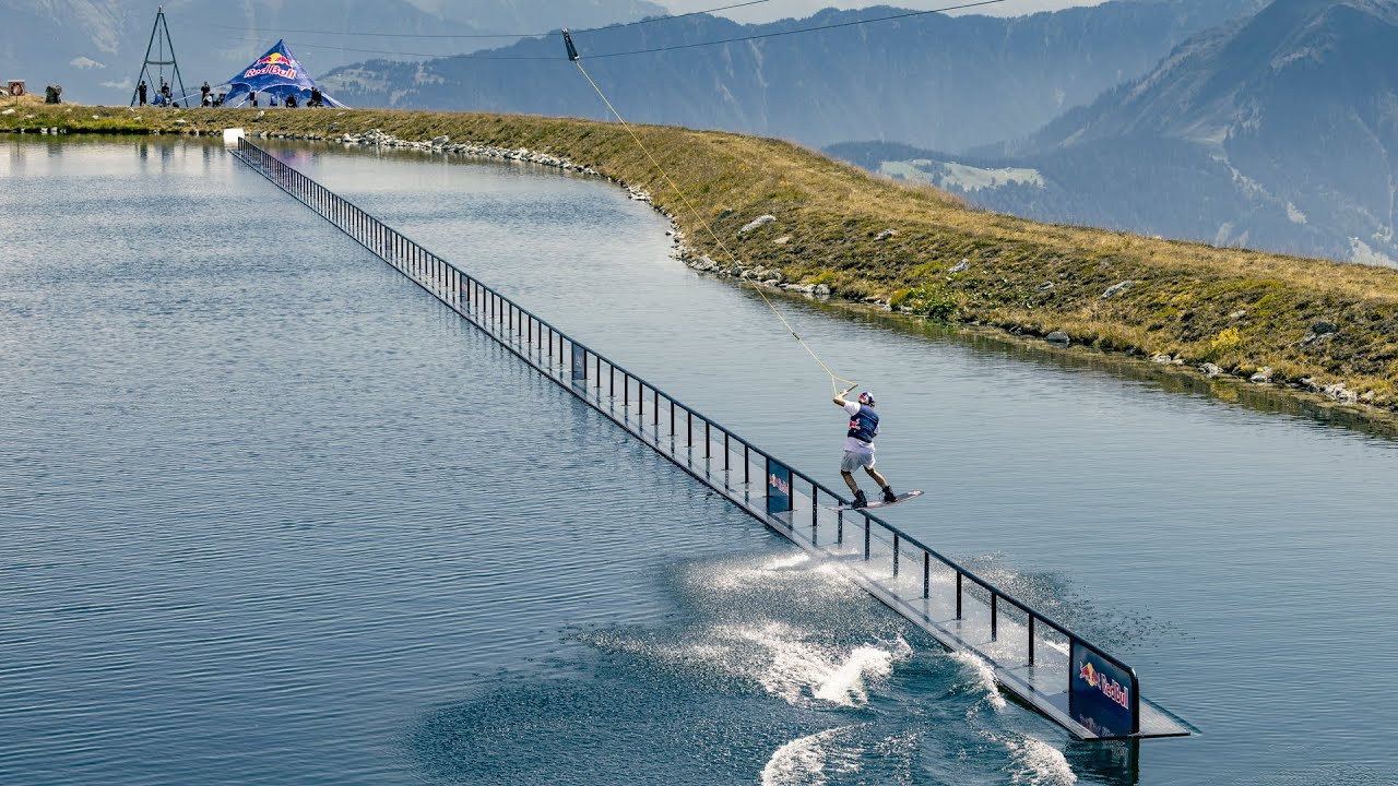 Jamie Huser from Switzerland has set a new wakeboarding world record, riding a 140-meter rail on Lake Falerin at 2,000 meters above sea level.<br /><br />The rail - built from 24 floating metal segments - is almost ten times the length of standard competition rails, demanding extraordinary balance, precision, and persistence from the 21-year-old, who succeeded on his 113th attempt.<br /><br />Key Facts<br /><br />* Athlete: Jamie Huser (SUI), age 21;<br />* New Record: 140-meter rail ride on a wakeboard;<br />* Location: Lake Falerin, Laax region, Switzerland - 2,000 m elevation;<br />* Attempts: 113 total - success on the final attempt;<br />* Speed: 34 km/h;<br />* Rail Construction: 24 floating metal segments, 140 meters in total length;<br /><br />The Challenge<br /><br />Wakeboarding rails in competition usually measure between 10 and 15 meters, built from plastic.<br /><br />Huser’s project was on another scale: a metal rail, 140 meters long, slicker than plastic and floating freely on an alpine lake.<br /><br />Maintaining balance and consistent rope tension proved the ultimate test. Speed had to stay precise, but rope pull varied along the rail.<br /><br />“I wanted to try something new and really challenge myself,” said Huser.<br /><br />On his 113th attempt, he held balance from start to finish, gliding all 140 meters.<br /><br />Technical and Physical Preparation<br /><br />Balance was key.<br /><br />Huser trained for months on slacklines, gym balls, and balance boards.<br /><br />He strengthened his arms and shoulders, especially his left shoulder, after recent surgery.<br /><br />On the rail, he made constant micro-adjustments in speed, stance, and positioning.<br /><br />The breakthrough came when he slowed his mindset. Huser explained: “I told myself, ‘Do it nice and slow, like in slow motion. Every tiny movement makes a difference.”<br /><br />The perfect pace: 34 km/h. And then, he nailed it.<br /><br />Footage: Red Bull
