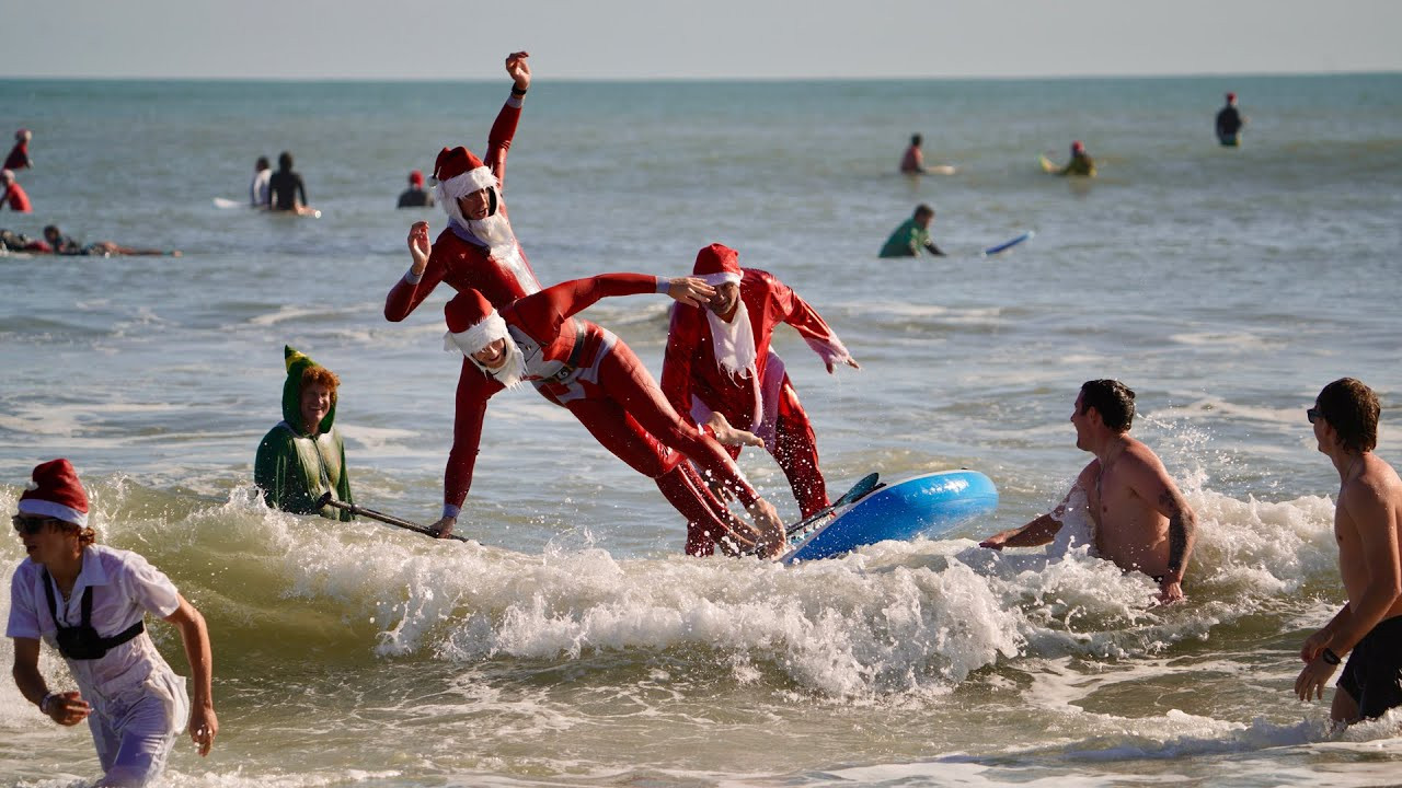 More than 10,000 people packed Cocoa Beach on Christmas Eve for the 2025 edition of Surfing Santas, one of Florida’s most recognizable holiday traditions.<br /><br />Hundreds of surfers suited up as Santa Claus, elves, and other festive characters, filling the water and the shoreline with red suits, surfboards, and holiday noise.<br /><br />Now in its 17th year, Surfing Santas began in 2009 as a small family surf by local surfer George Trosset.<br /><br />What started with one Santa and one elf has grown into a global spectacle, drawing thousands of spectators and around 500 costumed surfers in and out of the Atlantic.<br /><br />The day delivered all the classics, including the annual Santa helicopter jump, creative costume contests, and the crowd-favorite SUPsquatch, where four surfers rode a single board together.<br /><br />Near-perfect weather, live music, and nonstop smiles kept the beach buzzing all morning.<br /><br />Beyond the fun, Surfing Santas raises money for the Florida Surf Museum, Grind for Life, and Who We Play For, supporting cancer patients and heart health awareness.<br /><br />It’s part surf session, part holiday party, and all Cocoa Beach.<br /><br />Footage: NPI Productions / Dalton Smith